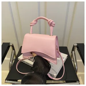 Pink PU leather shoulder crossbody bag with unique curved flap and stylish knotted handle.