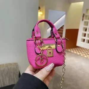 Mini pink top handle shoulder bag with metal lock and chain strap for women chic style.