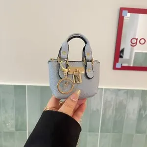 Detailed shot of mini blue leather handbag charm with gold hardware, padlock and handle design.