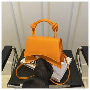 Orange shoulder handbag with unique curved bottom design, chic knotted handle and stylish strap.