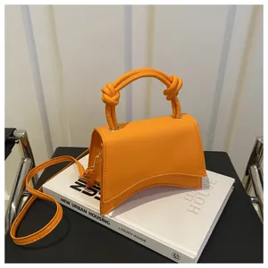 Detailed view of the solid color handbag featuring a unique curved base and knotted handle.