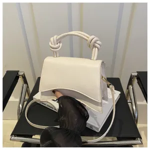 Stylish white handbag with knot handle and wavy flap, versatile crossbody bag for modern daily use.