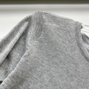 Détail de pull en tricot gris montrant un col texturé doux et la couture d'épaule.