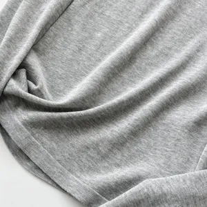 Vue rapprochée de la texture en tricot gris clair doux, montrant un tissu fin et subtil.