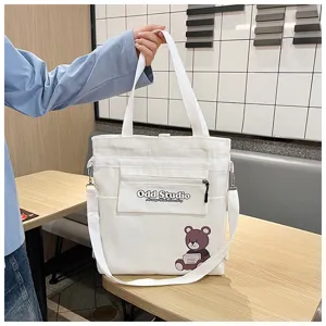 Nahaufnahme der weißen Canvas-Tragetasche mit Fronttaschen-Druck und Bären-Grafik.