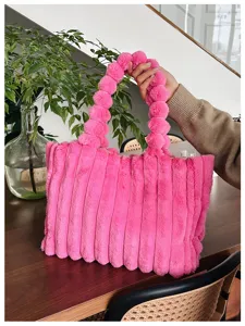 Pink fuzzy tote bag detail showing plush texture and pom-pom handle in cozy indoor setting.