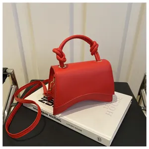 Red leather handbag for women, stylish curved design with top handle and shoulder strap.