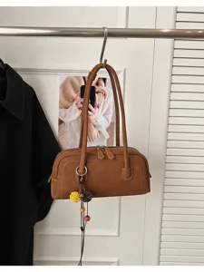 Brown retro shoulder pillow bag, classic commuting style with dual straps and charms.