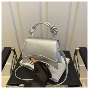 Detail shot of the silver leather handbag with unique curved bottom and knotted handle.