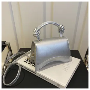 Silver metallic top handle shoulder bag with unique curved design and knotted handles chic.