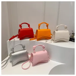 Detailed view of fashionable solid color handbags in multiple vibrant shades with curved base.
