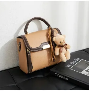 Contrast color leather handbag for women, chic shoulder bag with cute teddy bear charm detail.