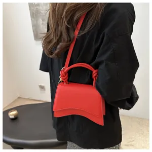 Stylish red PU leather shoulder handbag with unique curved design and knotted handle for women.