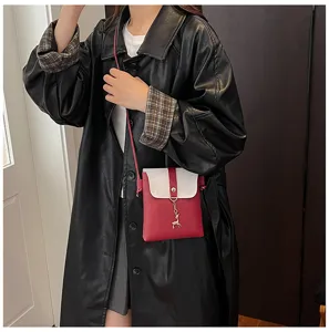 Detail view of stylish mini crossbody phone bag for women, red white contrast design with deer charm.