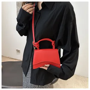 Close up detail shot of the stylish red mini handbag featuring a unique curved design and handle.