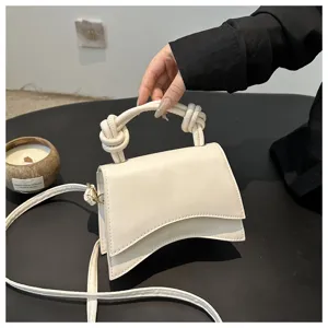 Elegant solid color women handbag with unique curved flap design and stylish knot handle.
