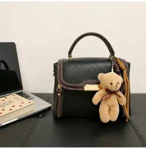 Stylish color-block women's shoulder handbag with top handle, cute bear charm and elegant design.
