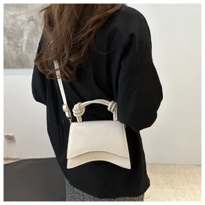 Detailed view of white shoulder bag with curved bottom and handle, elegant everyday style.