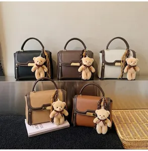 Detail view of multi-color colorblock shoulder handbags with cute bear pendants and scarves.
