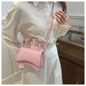 Pink crossbody bag detail showing curved flap and trendy knotted handle design for women.
