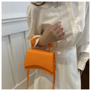 Orange top handle crossbody bag detail view, stylish curved bottom design for women fashion.