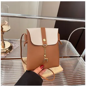 Mini crossbody phone bag with cute deer pendant, stylish brown and white shoulder bag.