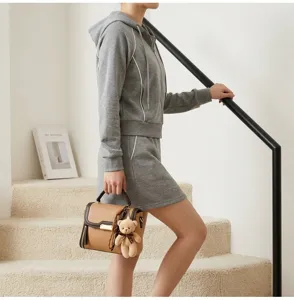Stylish contrast color handbag for women, elegant patchwork design with cute bear pendant.