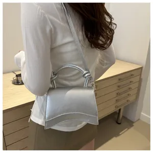 Details of stylish silver minimalist women shoulder handbag with curved design for daily commute.