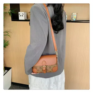 Stylish monogram shoulder bag with brown leather trim, versatile crossbody design for women.