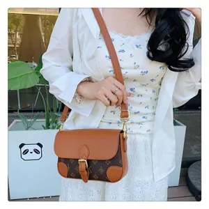 Detailed view of stylish brown leather shoulder crossbody bag with monogram flap and metal buckle.