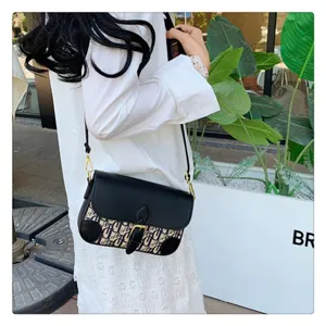 Detail view of stylish black flap monogram shoulder bag worn by model, trendy crossbody design.