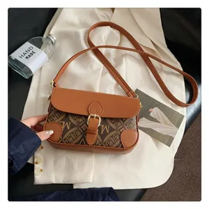 Detailed view of brown monogram crossbody shoulder bag featuring vintage print and gold buckle.