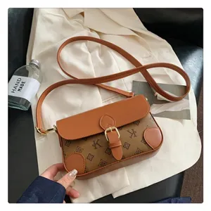 Detailed shot of brown vintage monogram crossbody bag with leather trim and gold buckle.