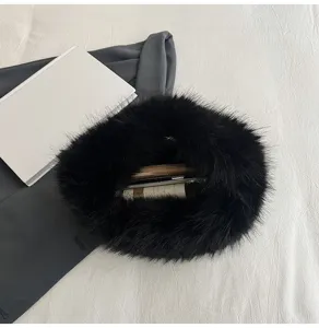 Dettaglio borsa a mano soffice nera, borsa invernale in pelliccia sintetica morbida ad anello.