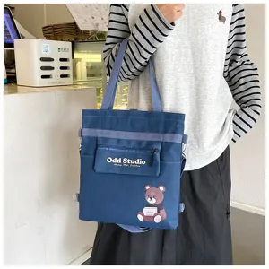 Detailansicht eines blauen Canvas-Rucksacks mit Bärenmotiv, Schultertasche und Vordertasche.