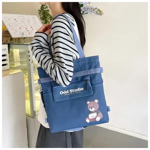 Detailansicht des blauen Canvas Rucksacks mit praktischer Fronttasche und Bärenmuster.