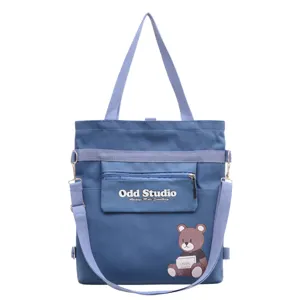 Detailansicht der blauen Segeltuchtasche mit Fronttasche, Trägern und süßem Bärenprint.