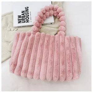 Stylish winter pink plush tote bag for women, soft furry shoulder bag with cute pom-pom handles.