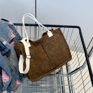 Stylish corduroy strawberry print tote bag with white handles for casual daily use.