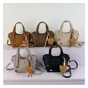 Details of stylish women leather tote bags in various colors with cute bear charms.
