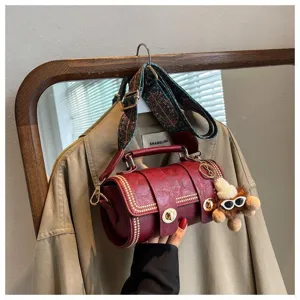 Retro rote Zylindertasche mit breitem Riemen und süßem Bärenanhänger Detailbild.