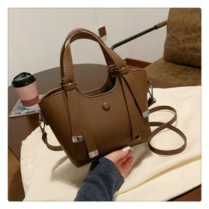 Detail view of brown PU leather tote shoulder bag featuring stylish metal buckles and handles.