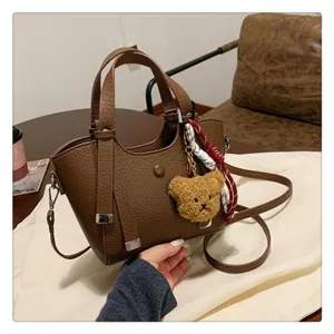 Elegant brown leather tote bag featuring a cute bear pendant and strap for daily commute.