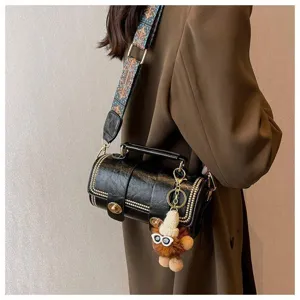 Detailansicht der retro Zylinder Umhängetasche für Damen mit breitem Gurt und Plüschpuppenanhänger.
