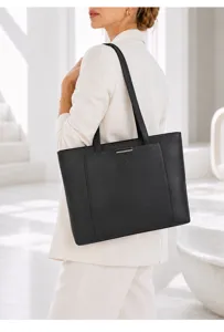 Detail view of black leather tote bag on shoulder, highlighting premium texture and commute style.