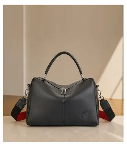 Detailed view of genuine leather Boston handbag, premium black cowhide texture, dual strap.