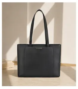 Detail view of the black leather tote bag showing textured cowhide and metallic closure accent.