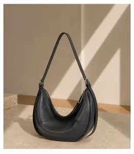 Close-up view of black genuine leather crescent underarm bag showing metal zipper detail.