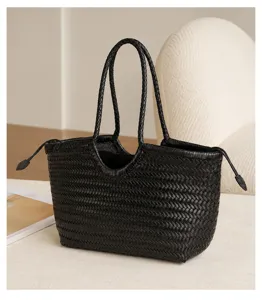 Black woven leather tote bag detail, featuring classic intrecciato design with dual handles.