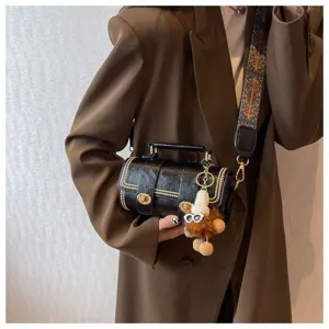 Schwarze Zylindertasche Vintage Umhängetasche mit breitem Gurt und süßem Plüsch-Anhänger für Damen.